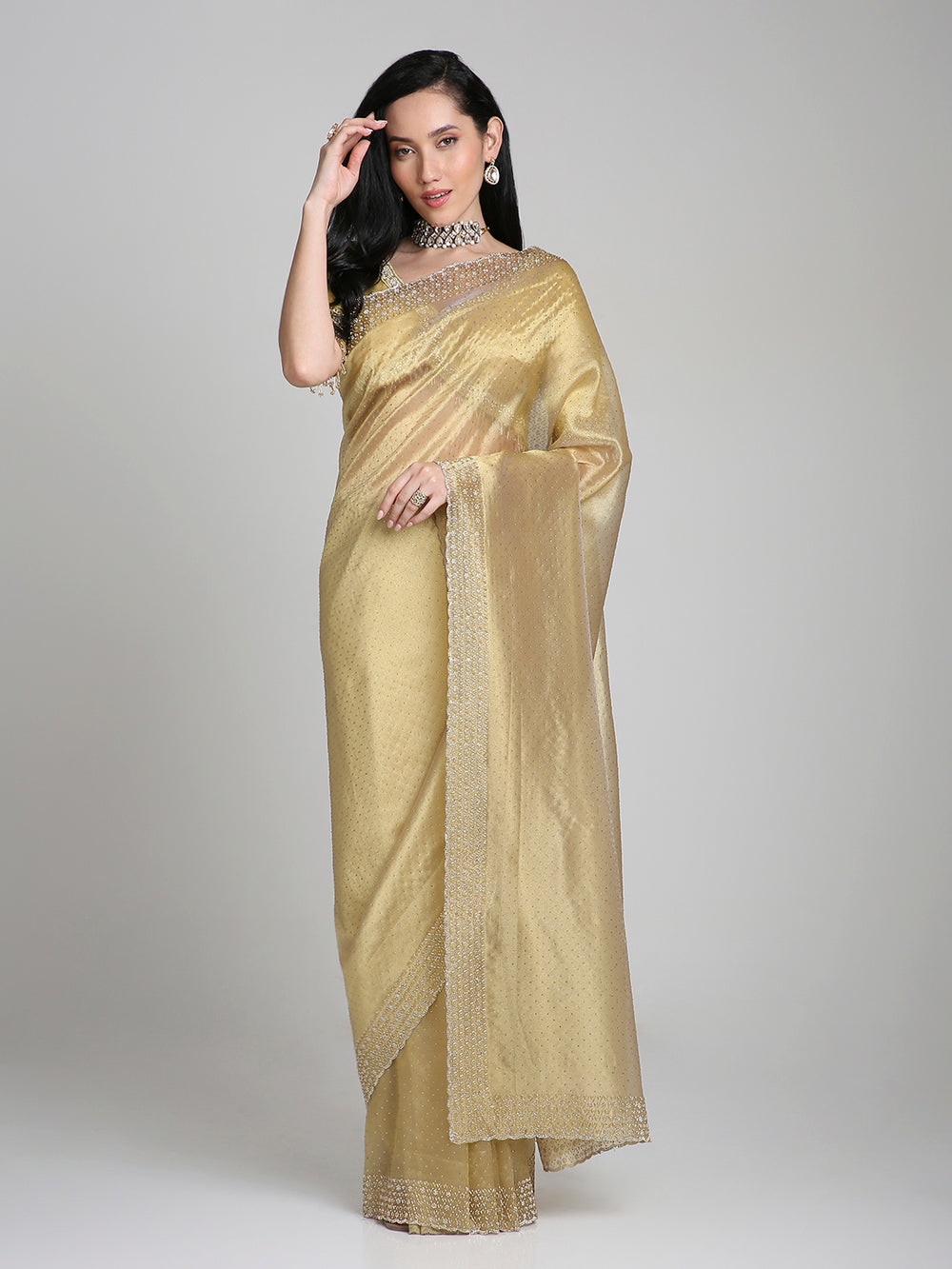 Woman wearing a gold saree with a plain background